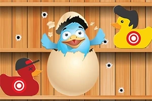 Pájaro azul emergiendo de un huevo entre dos patitos de goma con sombreros y objetivos en una pared de madera con agujeros de bala