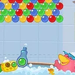 Patito verde y rosa en una bañera llena de burbujas, con una lámpara colgante y una fila de burbujas de colores en la parte superior