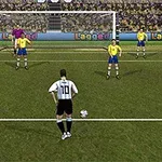 Jugador con camiseta blanca y negra se prepara para patear un penal frente a un portero y cuatro defensores en camiseta amarilla en una cancha de fútbol