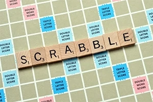 Fichas de madera con letras forman la palabra SCRABBLE en un tablero de juego con casillas de diferentes colores y valores