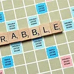 Fichas de madera con letras forman la palabra SCRABBLE en un tablero de juego con casillas de diferentes colores y valores