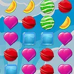 Dulces y frutas en forma de corazones rosados, rodajas de naranja, caramelos verdes y rojos, y cubos azules sobre un fondo azul con nubes